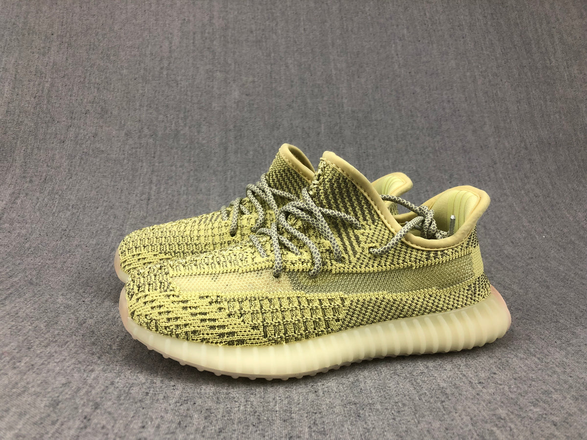 Pair of olive-yellow and black low-top sneakers positioned together on a gray background.