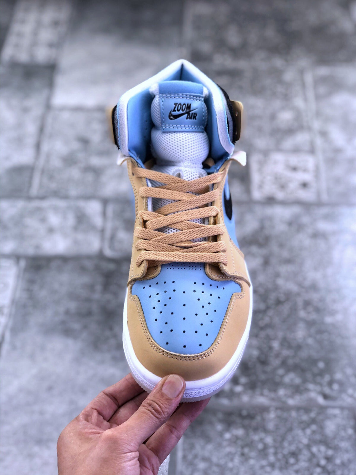 Top-down front view showing the perforated light blue toe box, tan laces, and padded tongue.