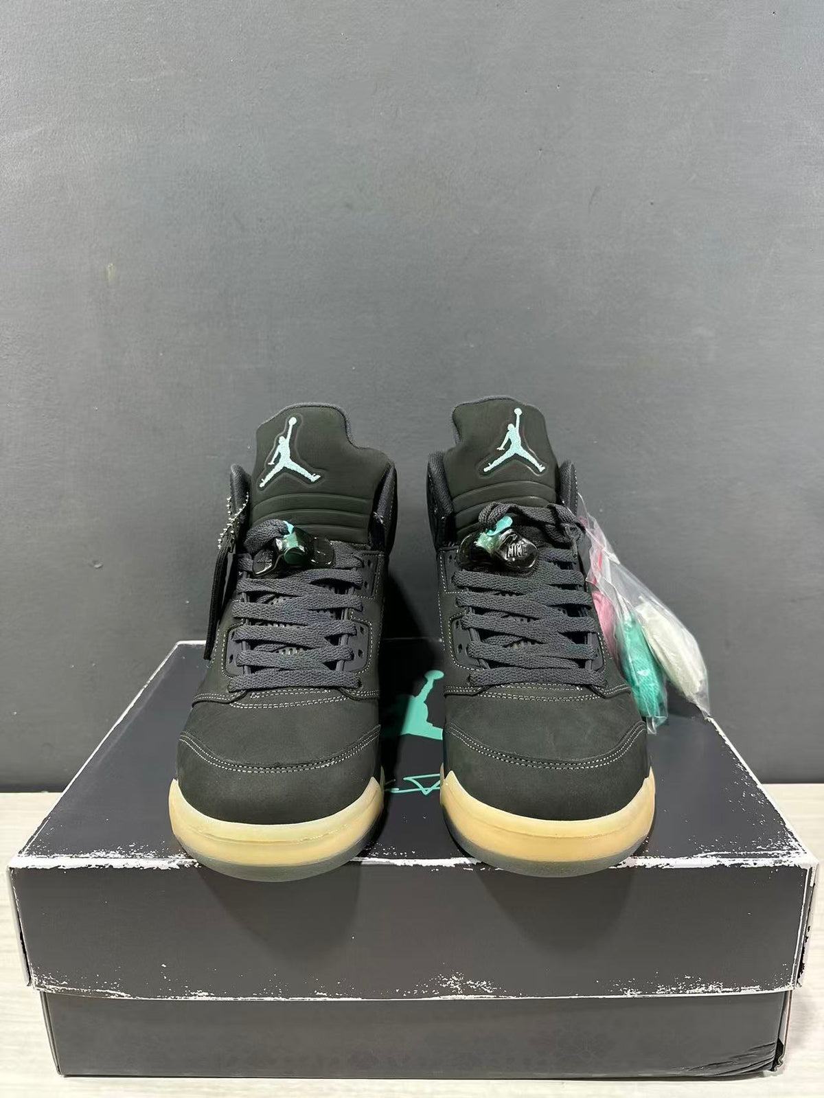 Front view of the Jordan Air Jordan 5 pair showing the tongue branding, black laces, dark green uppers, and translucent outsoles.