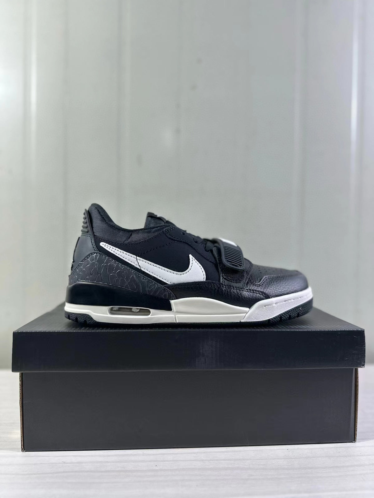 Single side profile showing the low-top silhouette, white side detailing, textured heel panel, and visible midsole window.