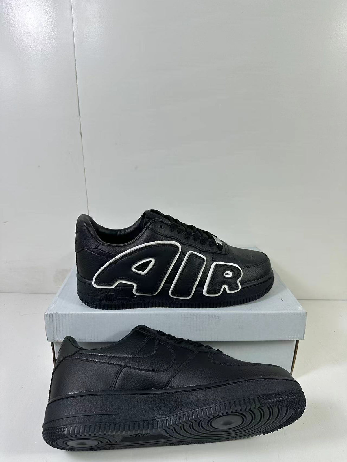 Black low-top sneakers shown from side and outsole angles, with one pair displaying AIR lettering and a circular-groove sole.