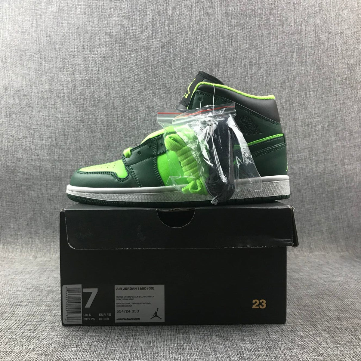 Side view of the sneaker on a black box with an additional lace bag; the box label shows EU 40, US 7, UK 6, CM 25, and style code 554724 330.