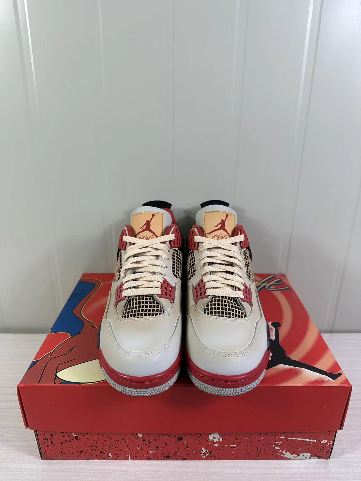 Front view of the Jordan Air Jordan 4 Retro pair showing the lace arrangement, tongue branding, and red toe accents.