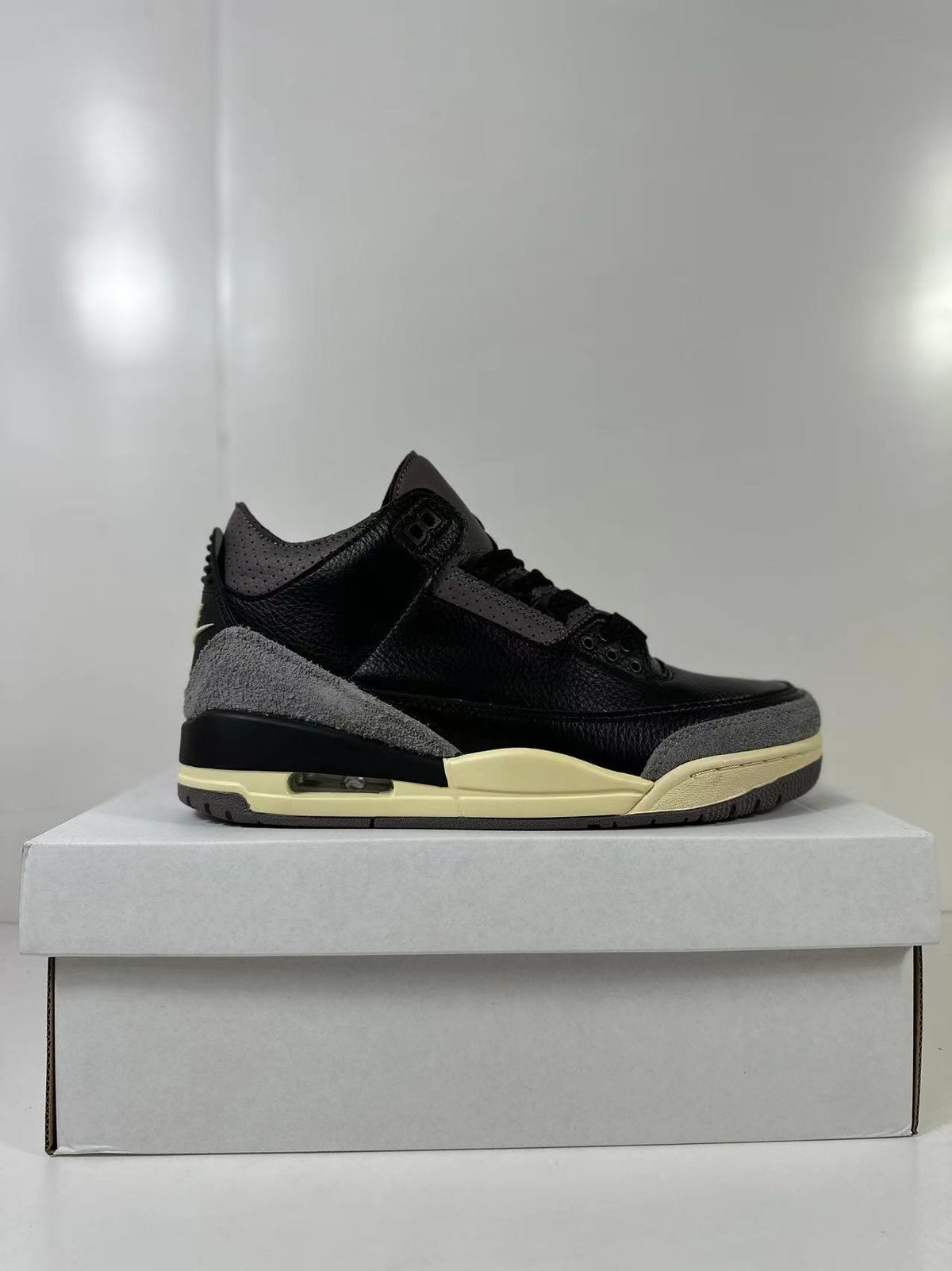 Side profile of the sneaker showing the lace area, layered overlays, cream midsole, and dark outsole.
