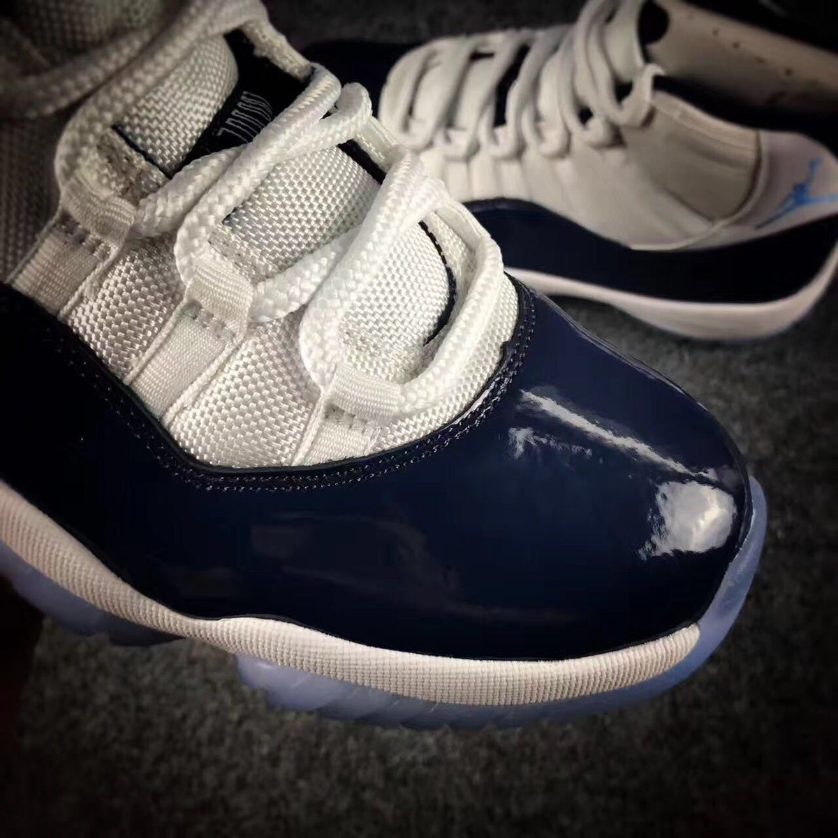 Close-up of the white laces, mesh tongue, stitching, and glossy navy toe overlay.