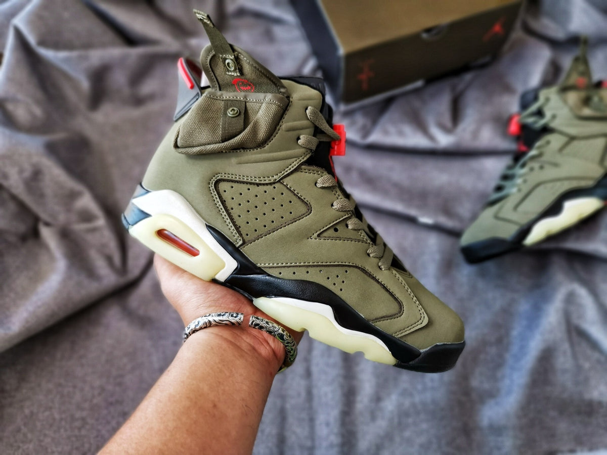 Close-up view of an olive Air Jordan 6 high-top sneaker showing layered panels, perforations, red accents, and a translucent outsole.