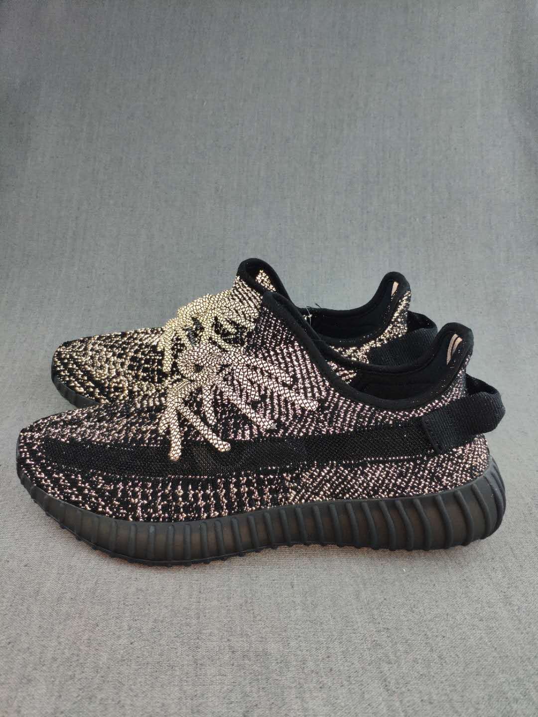 Side view of black Yeezy 350 V2-style sneakers with contrasting knit details and a black side band.