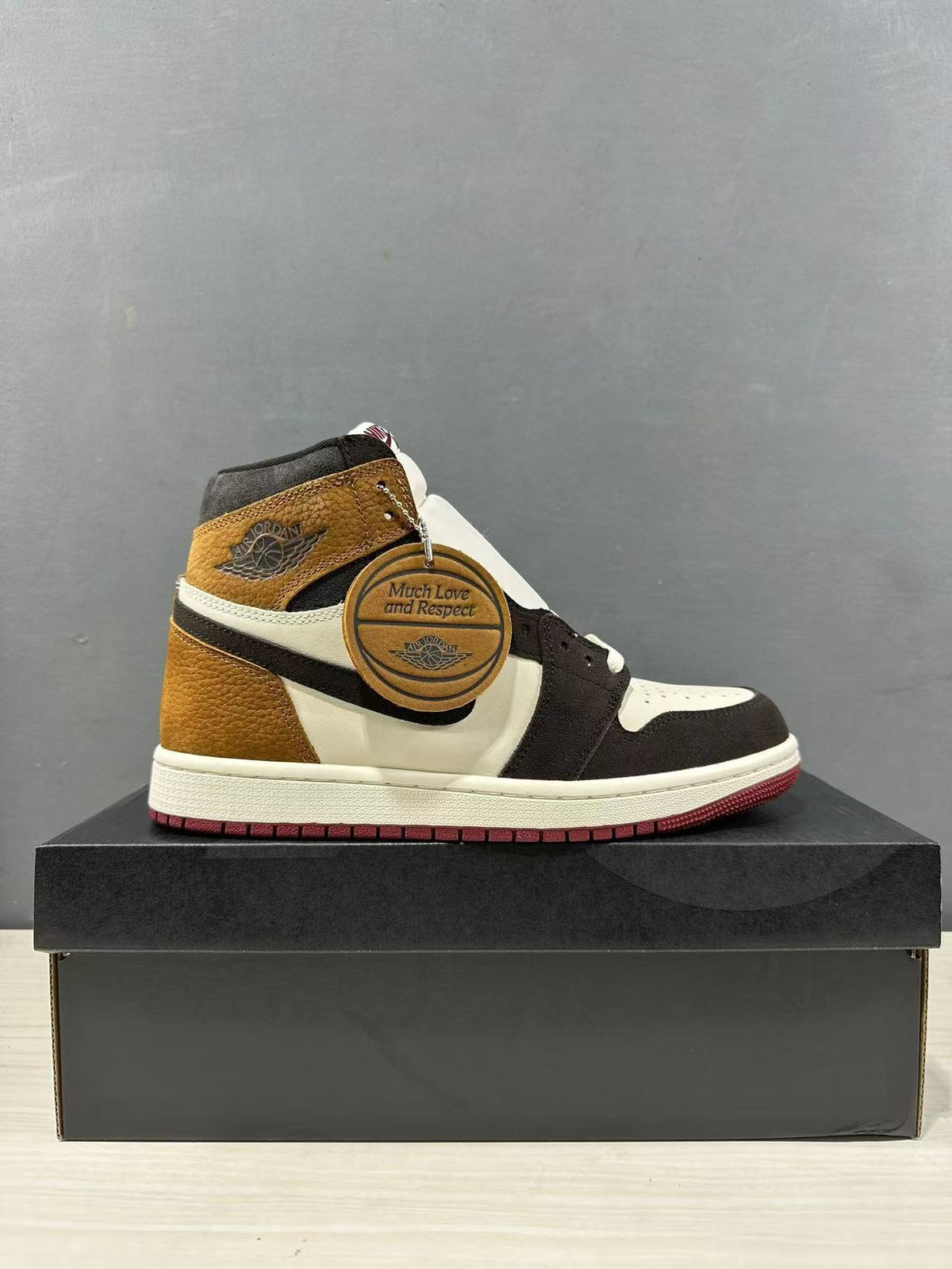 Side view of one high-top sneaker displaying the brown, black and white color blocking and burgundy outsole.