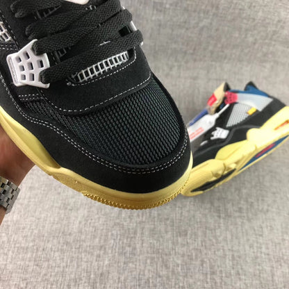 Close-up of the black mesh toe box, white stitching, black laces, and yellow-toned outsole.