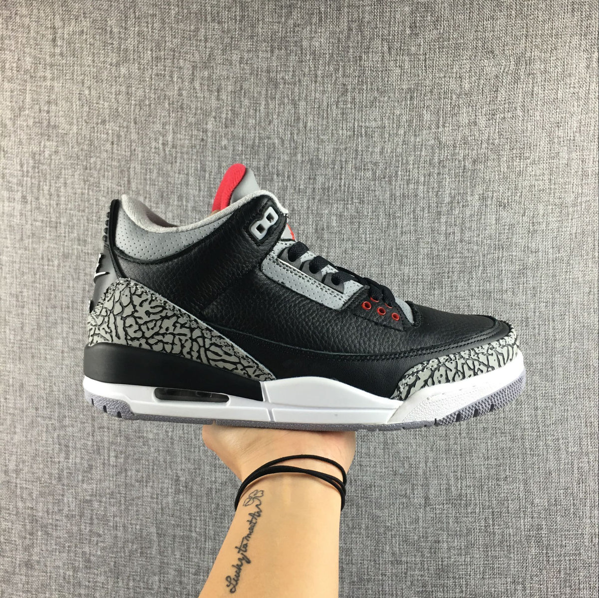 Air Jordan 3 Black Cement sneaker shown from the side above its shoebox; box label visible