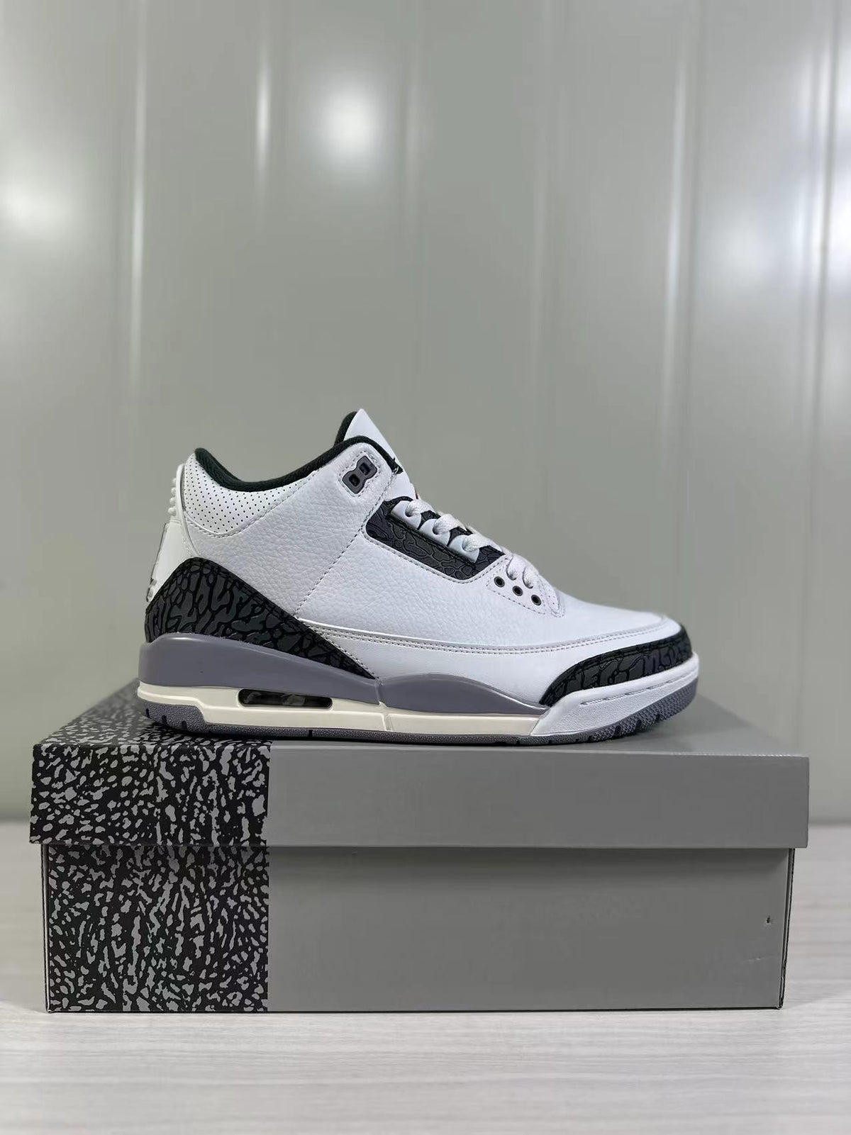Side profile showing the white upper, black elephant-print overlays, grey midsole, and visible outsole window.