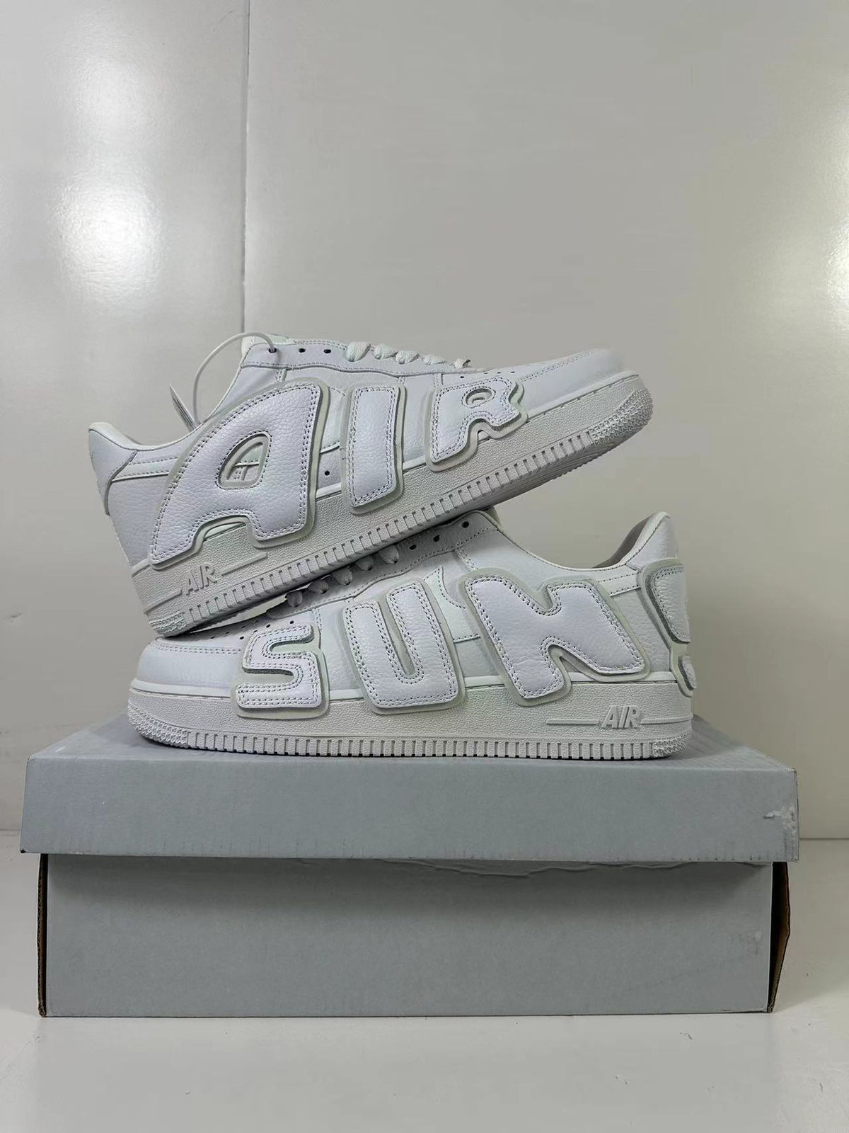 White sneaker pair arranged in a stacked side-profile display.