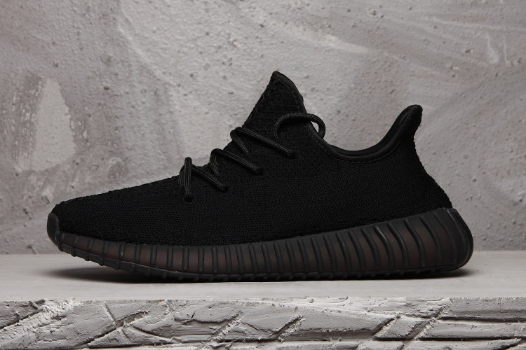 Side profile of a black low-top sneaker with a textured upper and dark ribbed outsole.