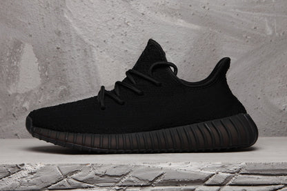 Side profile of a black low-top sneaker with a textured upper and dark ribbed outsole.