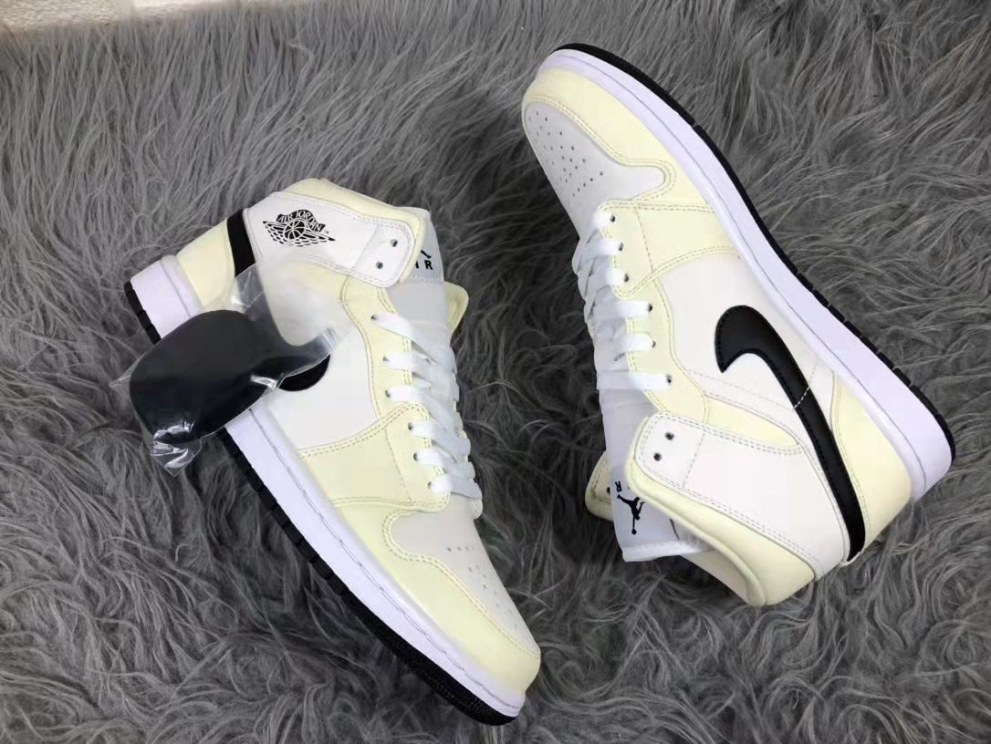 Two cream, white, and black mid-top sneakers arranged diagonally to show their side profiles and white midsoles.