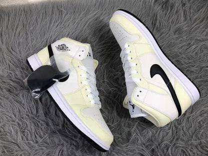 Two cream, white, and black mid-top sneakers arranged diagonally to show their side profiles and white midsoles.