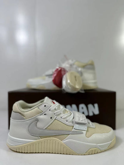 Three-quarter product view showing the cream and white upper, red spare laces, and gray heel detailing.