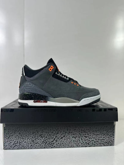 Side profile of one dark gray sneaker displaying the layered upper, elephant-print heel panel, speckled midsole, and orange-accented sole detail.