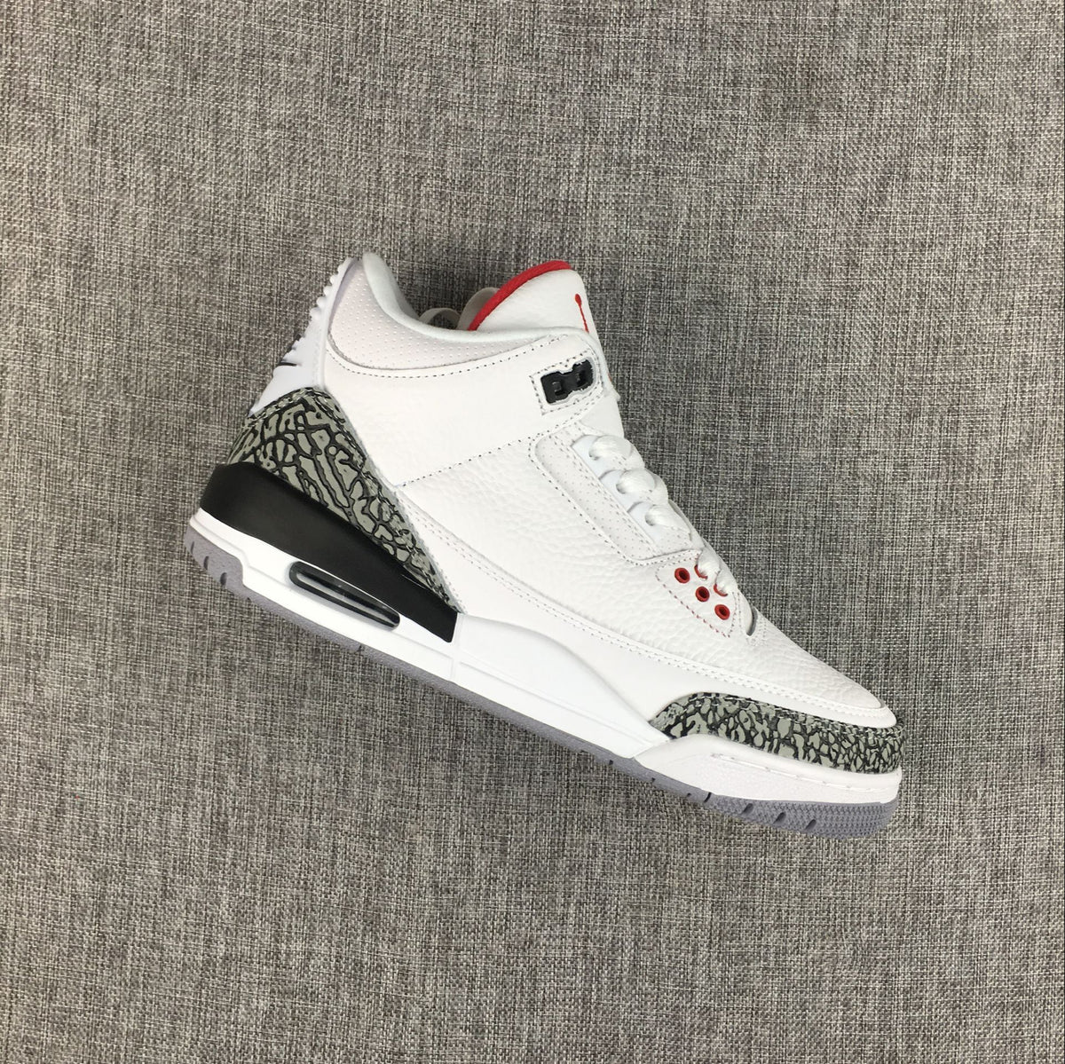 Angled view of the white and grey Jordan 3 sneaker showing elephant-print toe and heel overlays