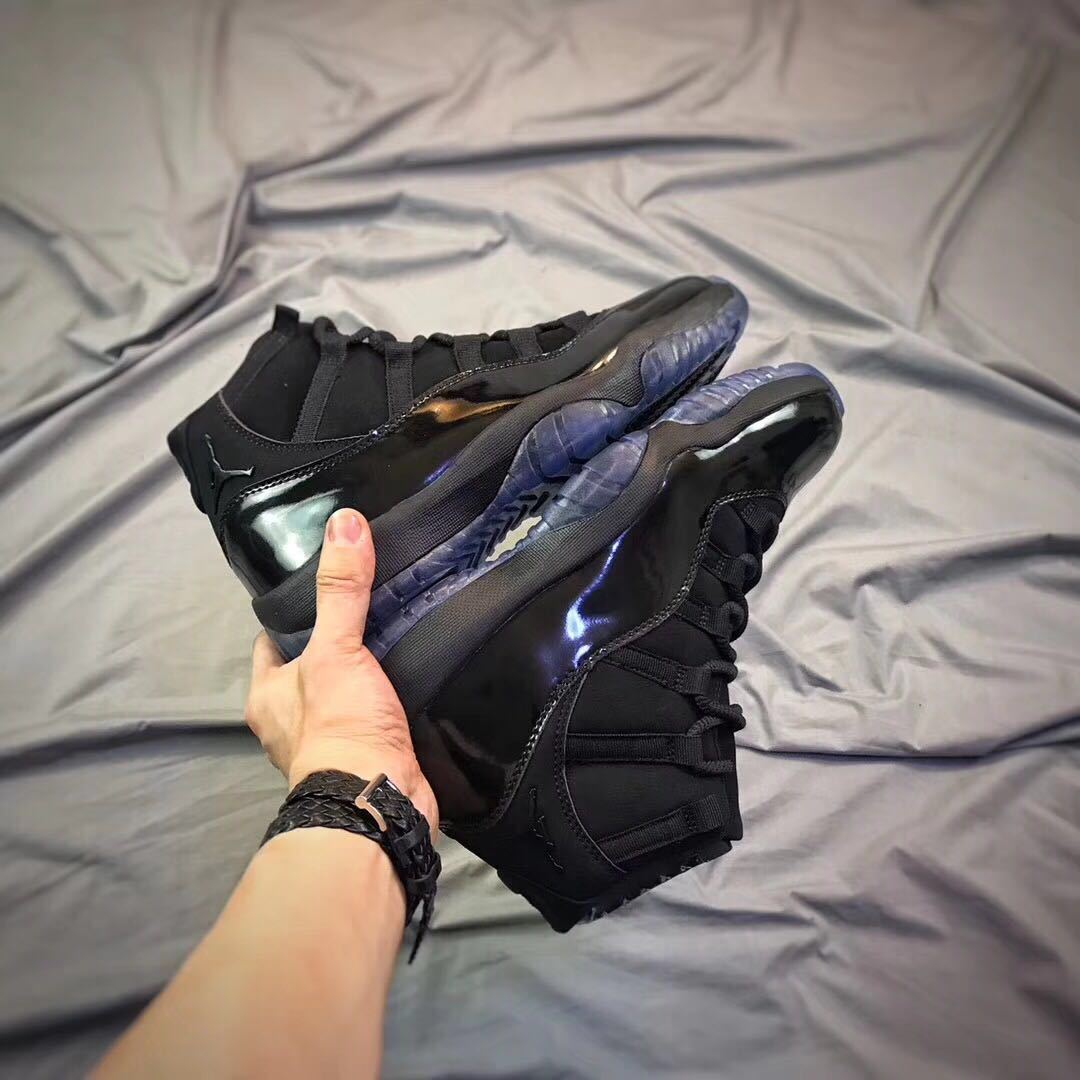 Black high-top sneakers held in hand, showing glossy side panels and translucent outsoles.
