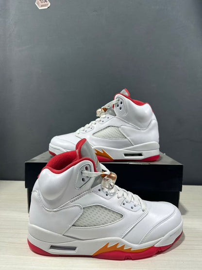 Two white high-top sneakers shown from side angles, highlighting padded collars, perforated panels and red-orange outsole details.