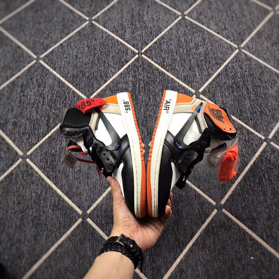 Top-down view of the pair showing black overlays, white panels, orange accents, and contrasting sole edges.
