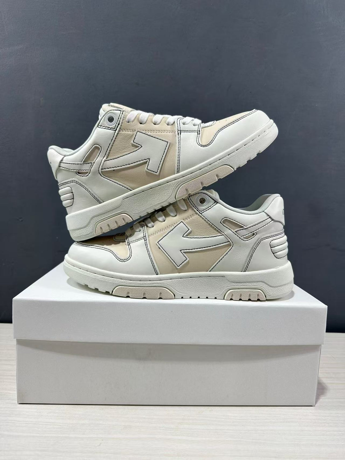 Two cream-white sneakers arranged one above the other to show the side design and outsole edge.