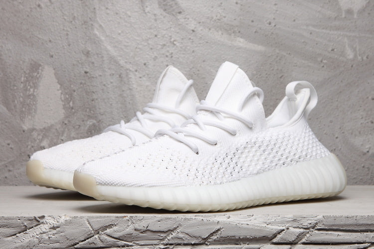Pair of white low-top sneakers shown from a front three-quarter angle with matching laces and textured uppers.