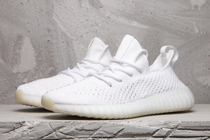 Pair of white low-top sneakers shown from a front three-quarter angle with matching laces and textured uppers.