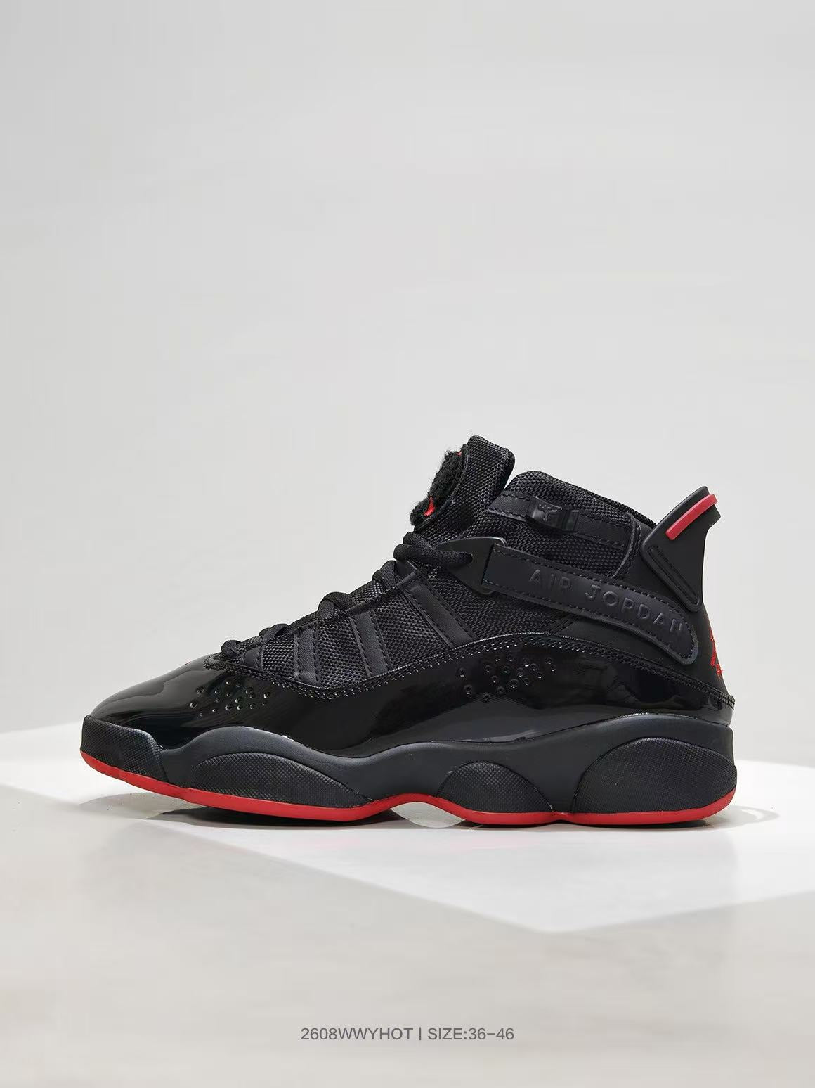 Side profile showing the black upper, glossy toe panel, ankle strap, and red outsole edge.