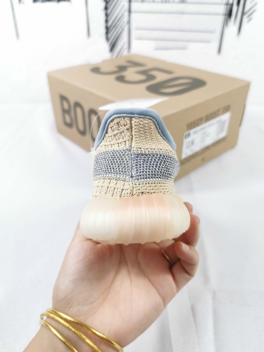 Rear view of the sneaker showing the gray heel stripe, blue-gray collar, translucent sole, and 350 box.