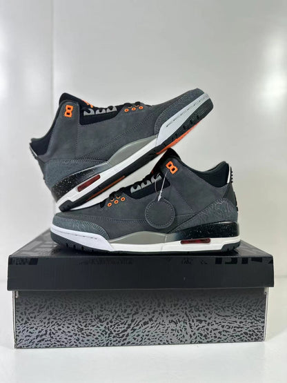 Three-quarter product view of the pair on the patterned shoe box, highlighting gray uppers, orange accents, elephant-print panels, and contrasting midsoles.