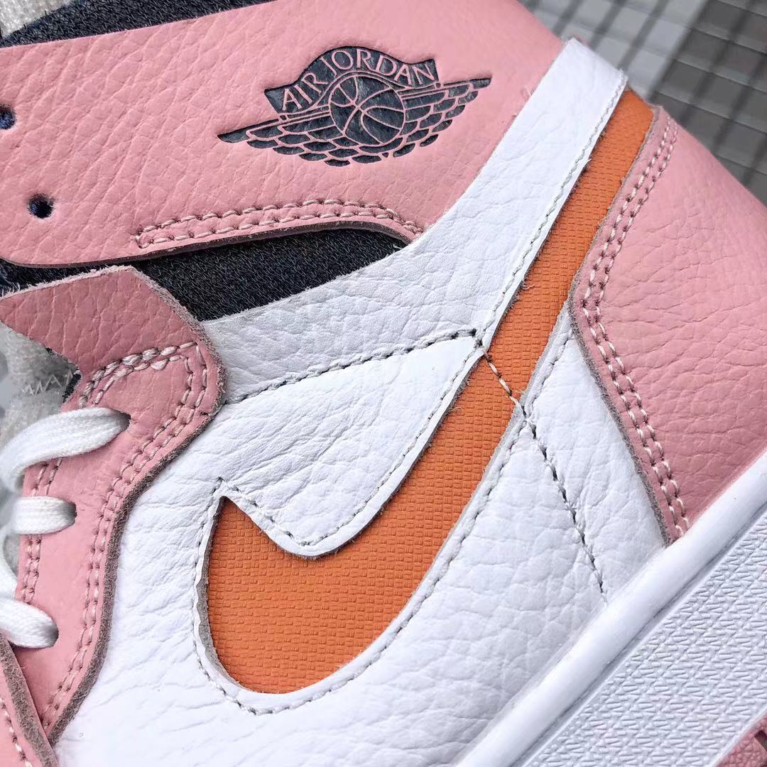 Close-up of the textured pink and white upper, orange side accent, stitching, and Jordan collar branding.