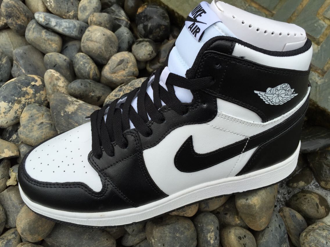 Close side view highlighting the black and white panel arrangement, perforated toe box, laces, and ankle emblem.