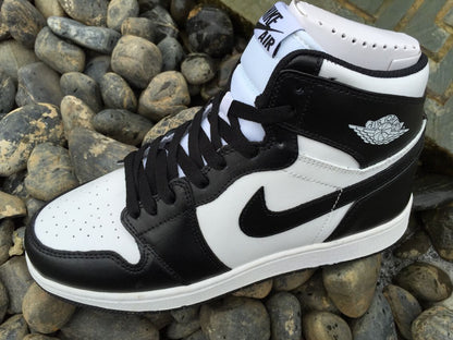 Close side view highlighting the black and white panel arrangement, perforated toe box, laces, and ankle emblem.