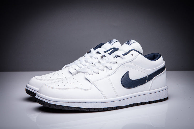 Front three-quarter view of a pair of white low-top Jordan sneakers with dark collar details.