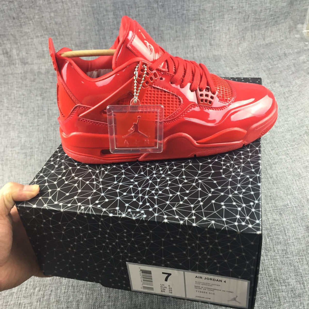 Single red sneaker displayed on a patterned box beside a clear Jordan display tag; the box label shows EU 40.