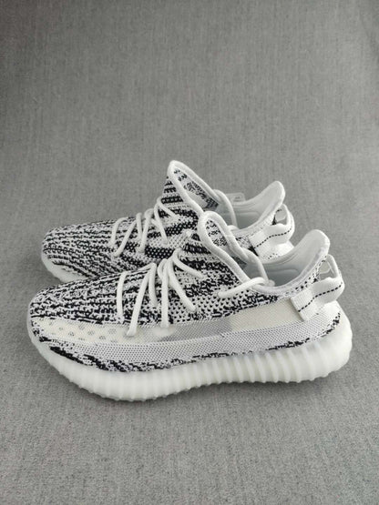 Pair of black-and-white patterned knit sneakers with white laces and translucent ribbed soles.