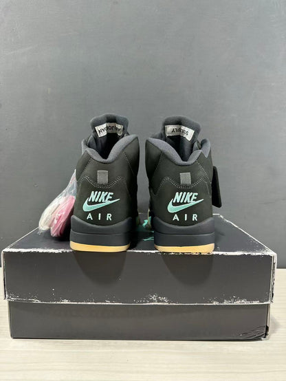Rear view of a pair of dark green and black Jordan Air Jordan 5 sneakers showing Nike Air branding and padded collars.