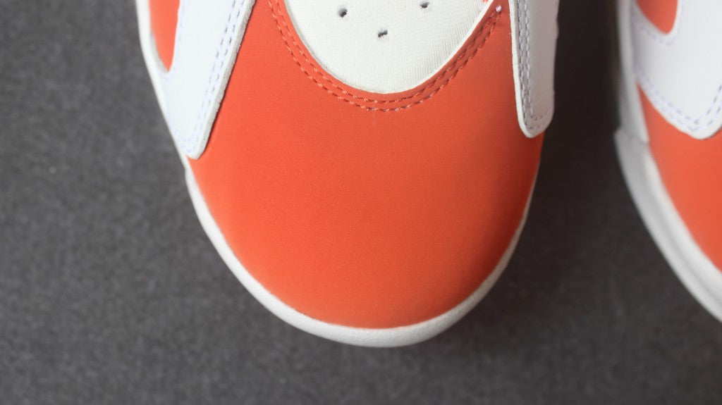 Close-up of the orange perforated toe box and surrounding white trim.