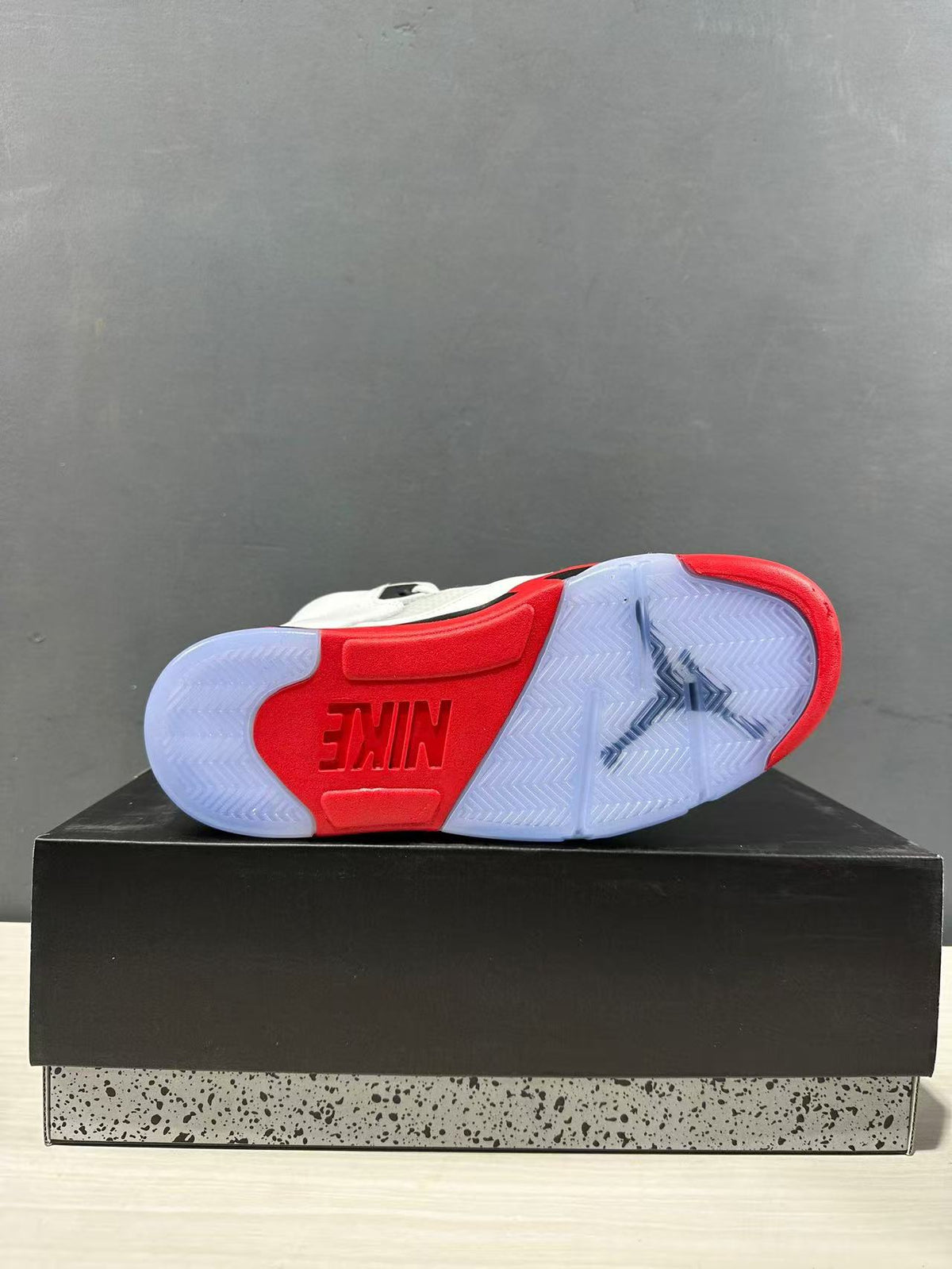 Outsole view showing translucent rubber sections, red traction areas, herringbone tread, and a central Jordan design.