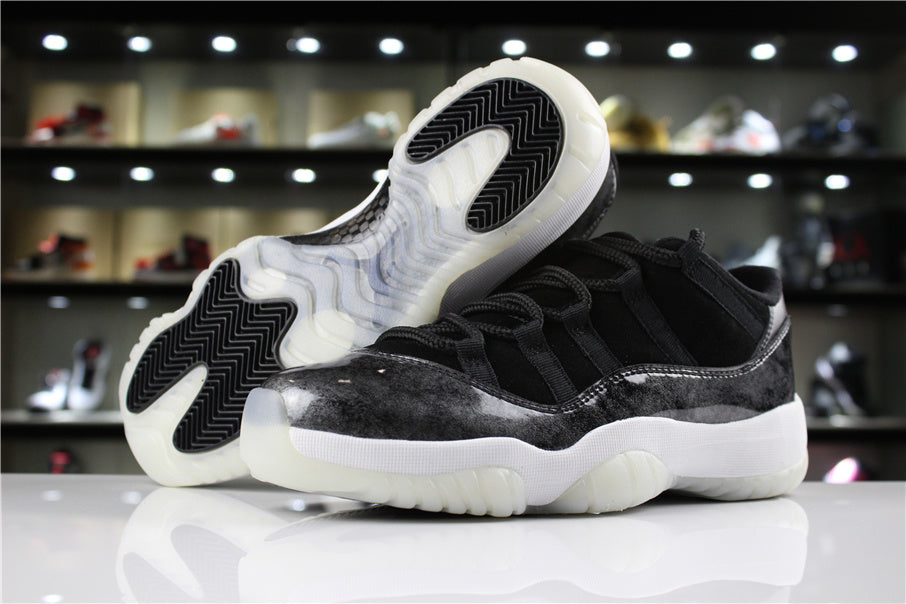 Three-quarter product view showing black and silver low-top sneakers with white midsoles and translucent outsoles.
