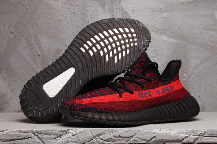Red and black knit sneaker shown in side profile with the outsole of a second shoe visible above it.