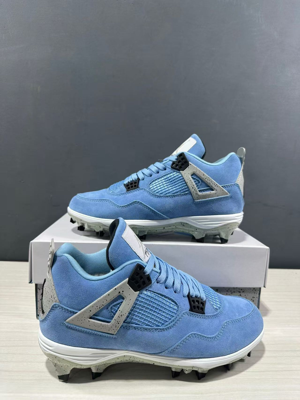 Three-quarter side view showing the blue uppers, mesh panels, molded side wings, and studded soles.