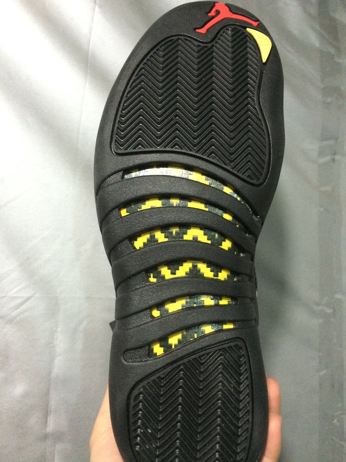 Full outsole view showing black herringbone tread, yellow patterned inserts, and a red Jordan logo.