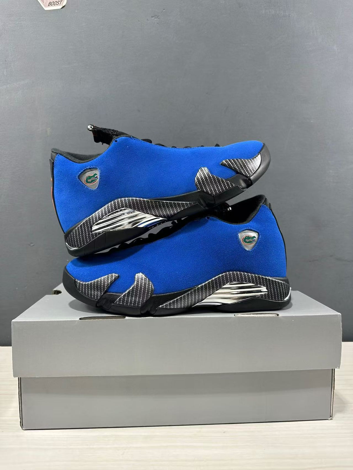 Pair of blue Jordan Air Jordan 14 Retro sneakers stacked on a box, showing Florida Gators emblems and contrasting black and silver details.