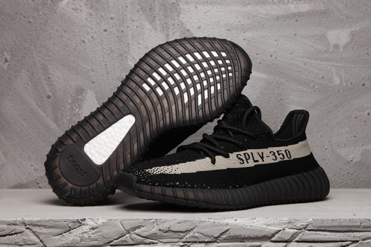 Side view of black Yeezy 350 V2 sneakers with a light stripe, SPLY-350 lettering and ribbed sole.