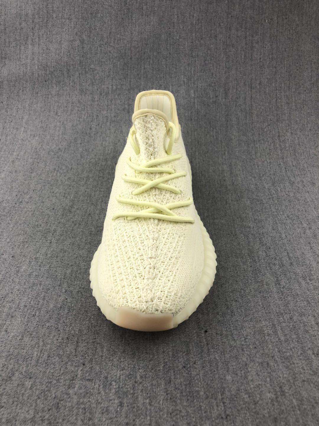 Front view of the pale cream sneaker showing tonal laces and the textured knit-style upper.