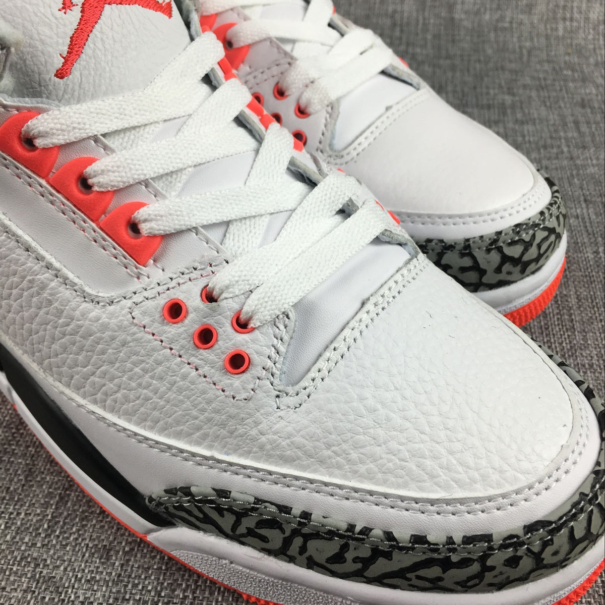 Close-up of the white laces, red eyelets, and elephant-print toe overlay.