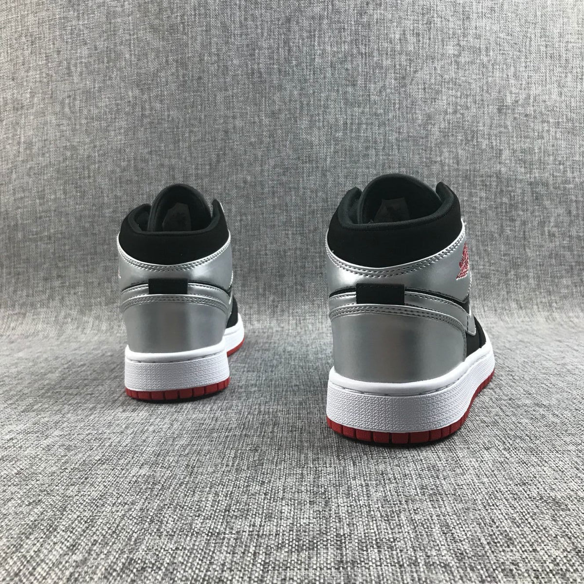 Rear view of the pair showing metallic silver heel panels, black collars, white midsoles and red outsoles.